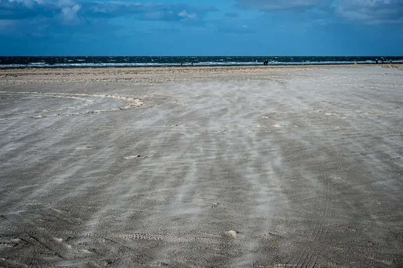 Sand blåser över en bred strand på Rømø i Sydjylland
