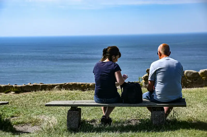 Två personer sitter på en bänk med utsikt över havet på Bornholm