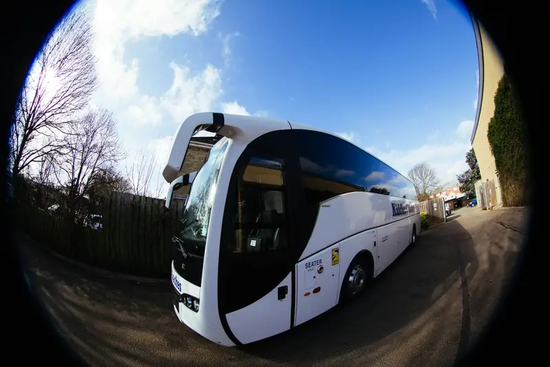 Vit turistbuss parkerad utomhus i soligt väder