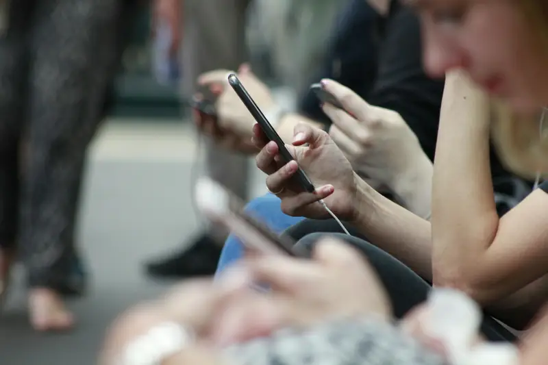 Resenärers händer med mobiltelefoner i väntan på tåg