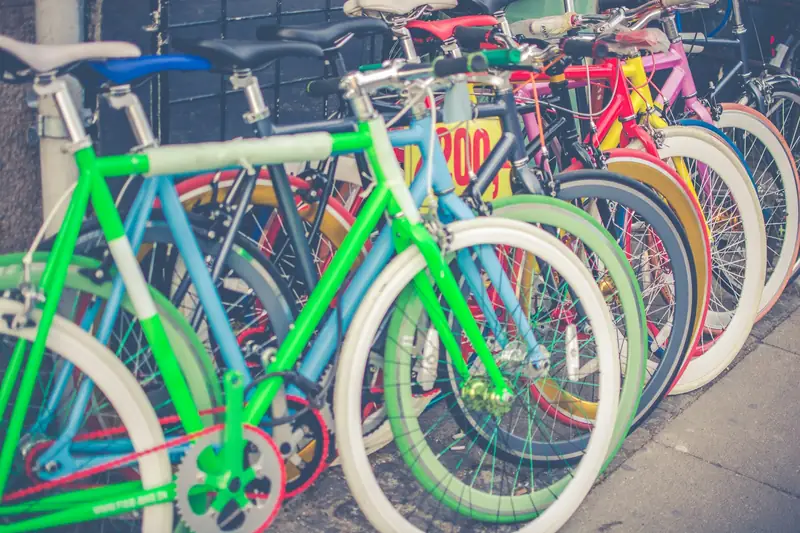 Flera färgglada cyklar parkerade på grå stenläggning