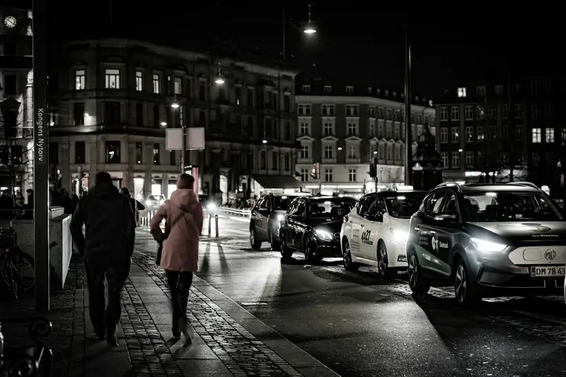 Svartvit kvällsbild av taxibilar och gata vid Kongens Nytorv