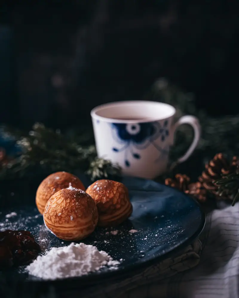 Æbleskiver på blå tallrik bredvid en kopp