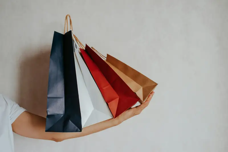 Hand som håller färgade shoppingpåsar