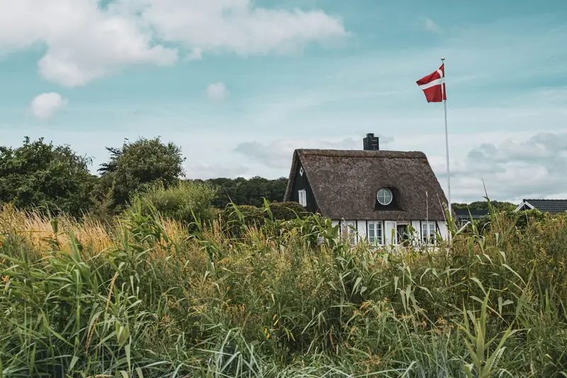 Danskt hus med halmtak och flagga vid Grønninghoved Strand